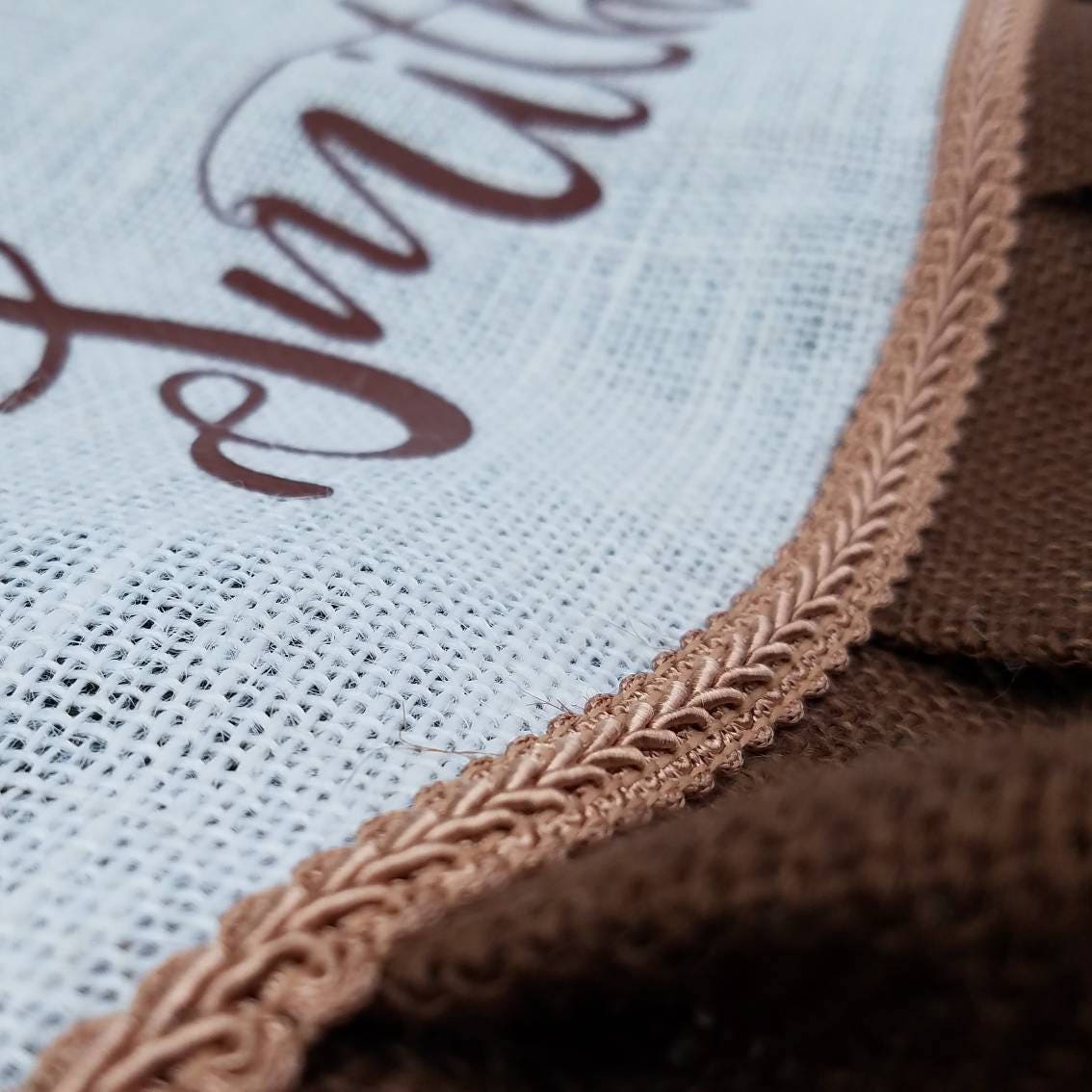 Close up of white christmas tree skirt with chocolate outer ruffle and toffee colored trim.