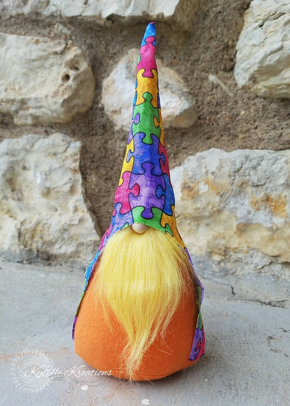 Autism Awareness Gnome with colorful puzzle piece hat, yellow beard and orange body.