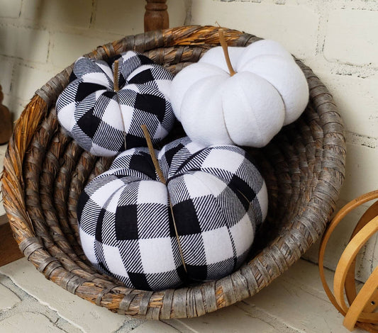 Black and white Buffalo plaid Halloween or Fall handmade fabric pumpkins.  Trio comprised of one large and one small in plaid print, with third in solid white color. Displayed in hand woven basket.