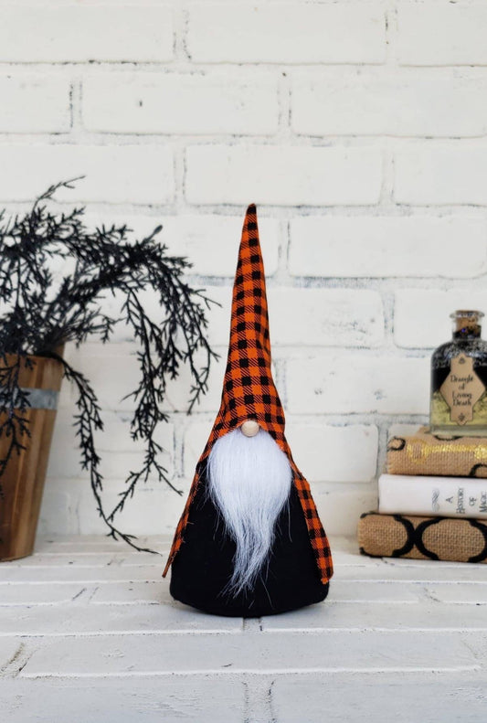 Halloween Gnome with black & orange buffalo plaid hat, white beard & black body. This handmade KyElle Kreations gnome measures 9 inches.. Displayed with faux foliage and seasonal accent decor.