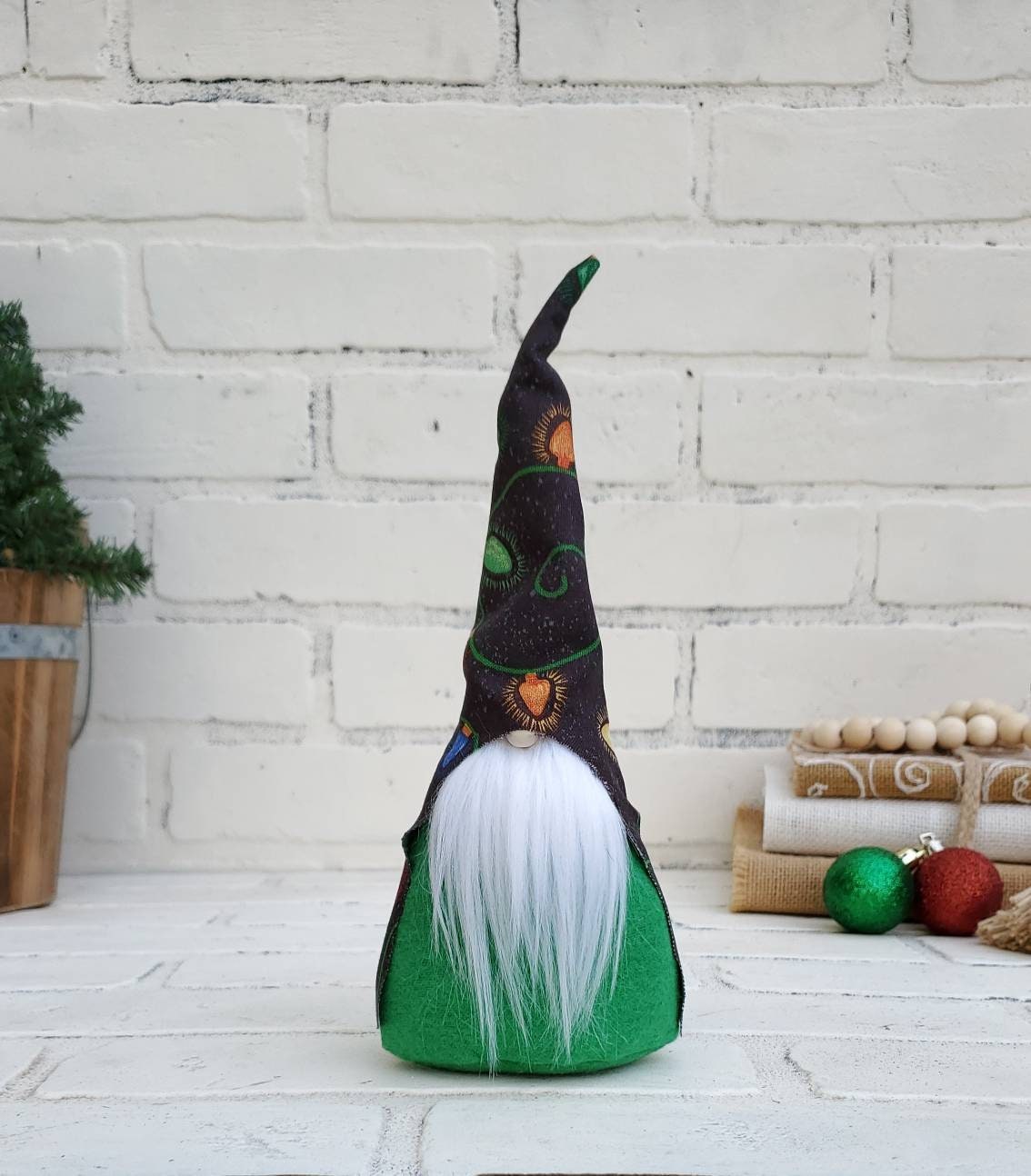Christmas Light Gnome with white beard & green body. This handmade KyElle Kreations gnome measures 9 inches.. Displayed with faux foliage and seasonal accent decor.