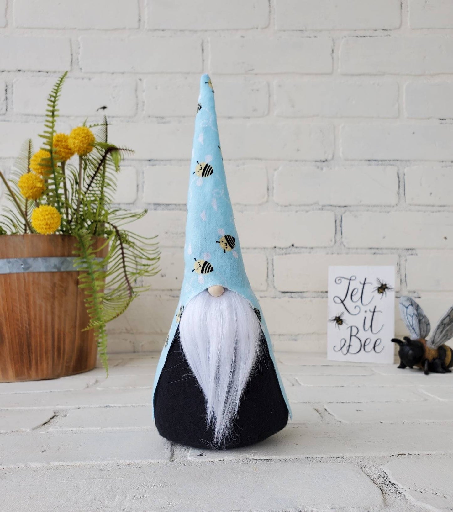 Bumble Bee Gnome with white beard & black body. This handmade KyElle Kreations gnome measures 9 inches.. Displayed with faux foliage and seasonal accent decor.