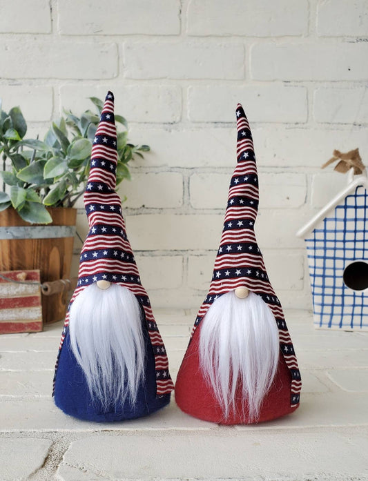 Two Patriotic Gnomes with white beards. 9inch handmade KyElle Kreations home decor Gnomes with primitive colored striped flag hats with burgundy & navy bodies. Displayed with faux foliage and seasonal accent decor.