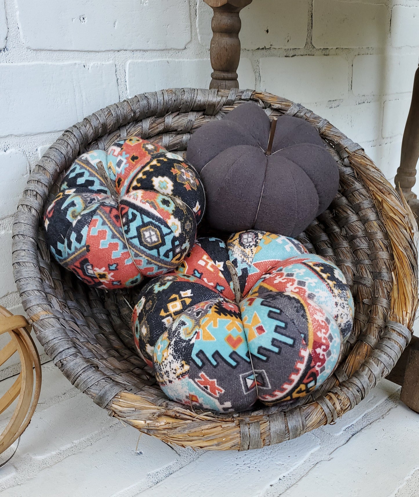 Handmade Pumpkin trio set crafted from Boho Aztec distressed print. One large and one small in boho print in gray, burgundy and soft teal hues. Third small pumpkin in solid gray color. Displayed in hand woven basket