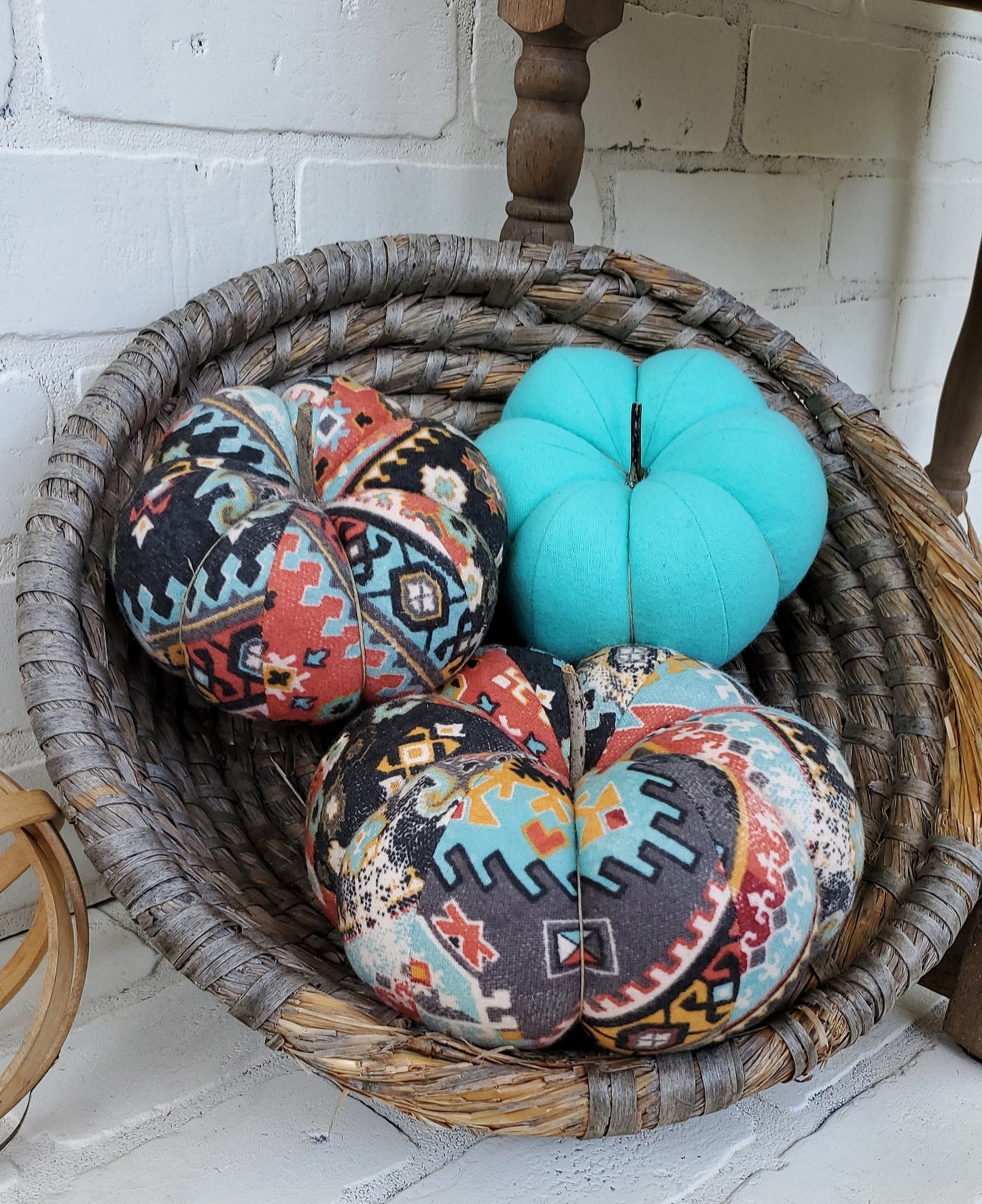 Handmade Pumpkin trio set crafted from Boho Aztec distressed print. One large and one small in boho print in gray, burgundy and soft teal hues. Third small pumpkin in solid aqua color. Displayed in hand woven basket