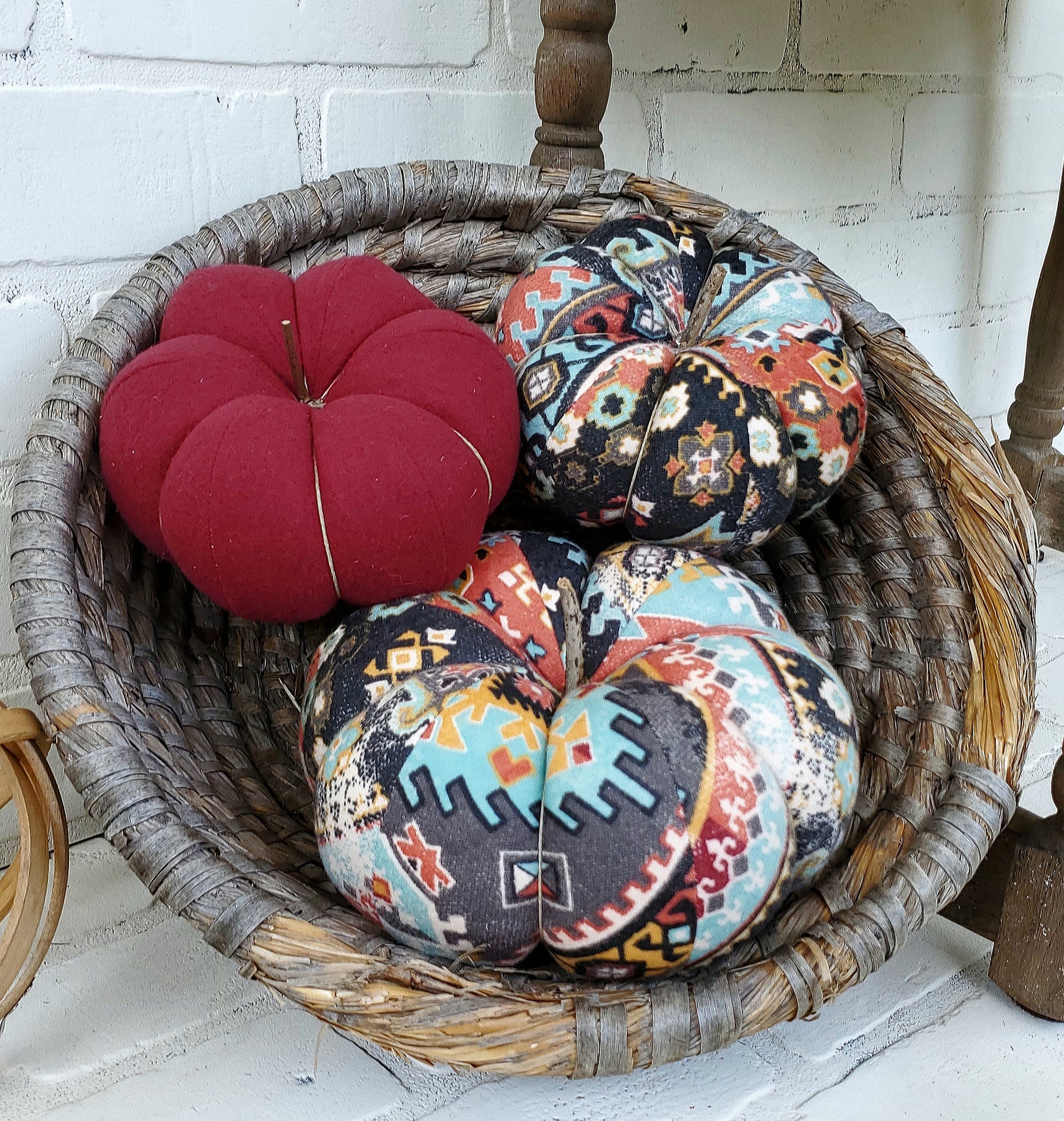 Handmade Pumpkin trio set crafted from Boho Aztec distressed print. One large and one small in boho print in gray, burgundy and soft teal hues. Third small pumpkin in solid burgundy color. Displayed in hand woven basket