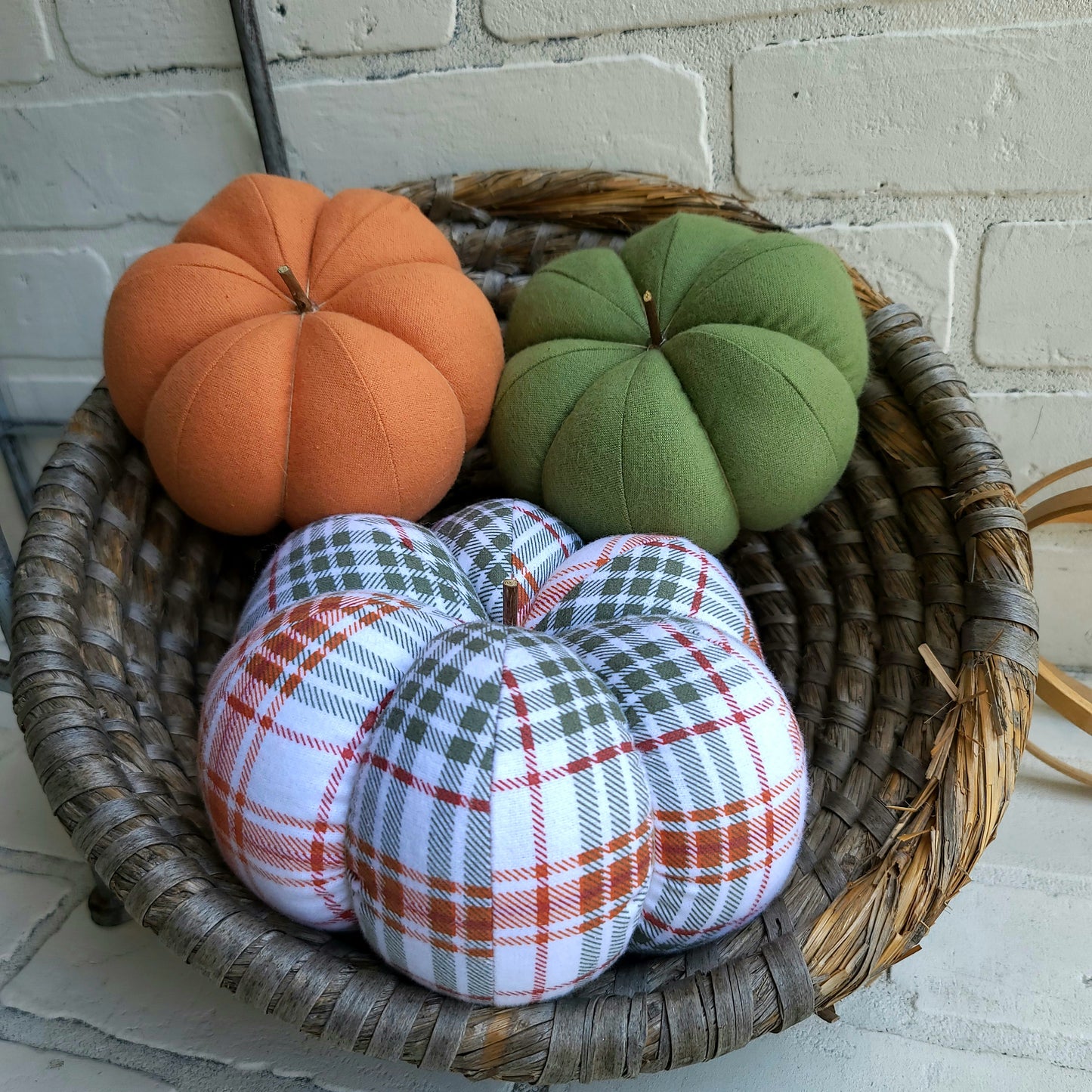 Pumpkin trio set in Fall plaid colors of burnt orange, sage and white. With one large plaid and two small in burnt orange and sage solid colors.Displayed in hand woven basket