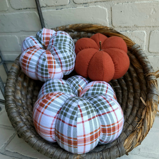 Pumpkin trio set in Fall plaid colors of burnt orange, sage and white. With one large and one small in plaid with one solid in burnt orange color. Displayed in hand woven basket