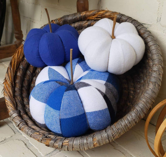 Handmade Pumpkin Trio with large pumpkin in Royal Blue, white & black buffalo plaid print. with 2 accenting small pumpkins in solid blue and a solid white. Displayed in round woven basket.