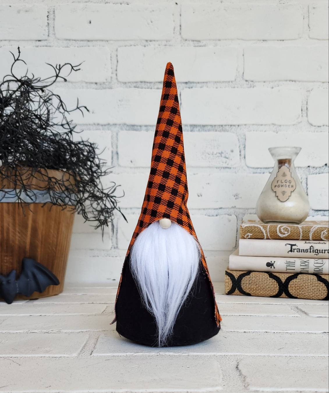 Halloween Gnome with black & orange buffalo plaid hat, white beard & black body. This handmade KyElle Kreations gnome measures 9 inches.. Displayed with faux foliage and seasonal accent decor.