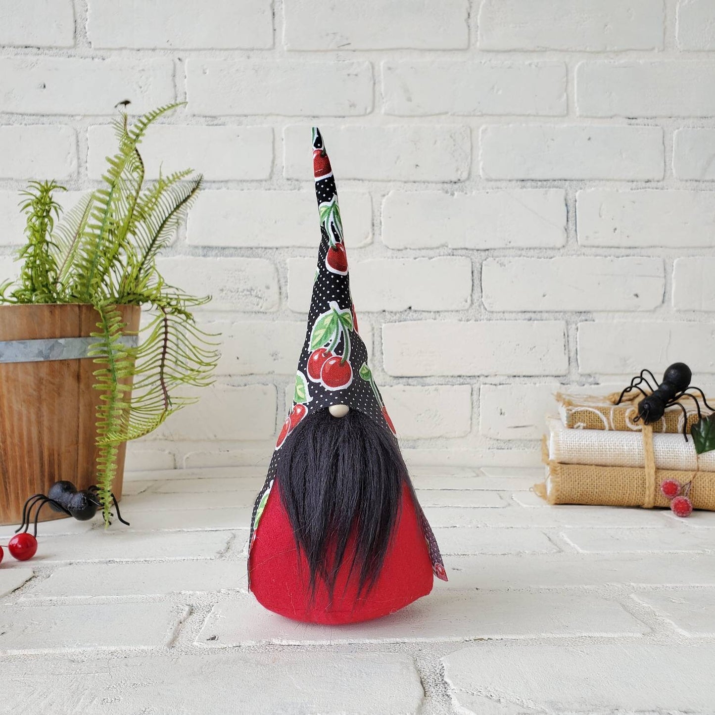 Cherry Gnome with black beard & red body. This handmade KyElle Kreations gnome measures 9 inches. Displayed with faux foliage and seasonal accent decor. 