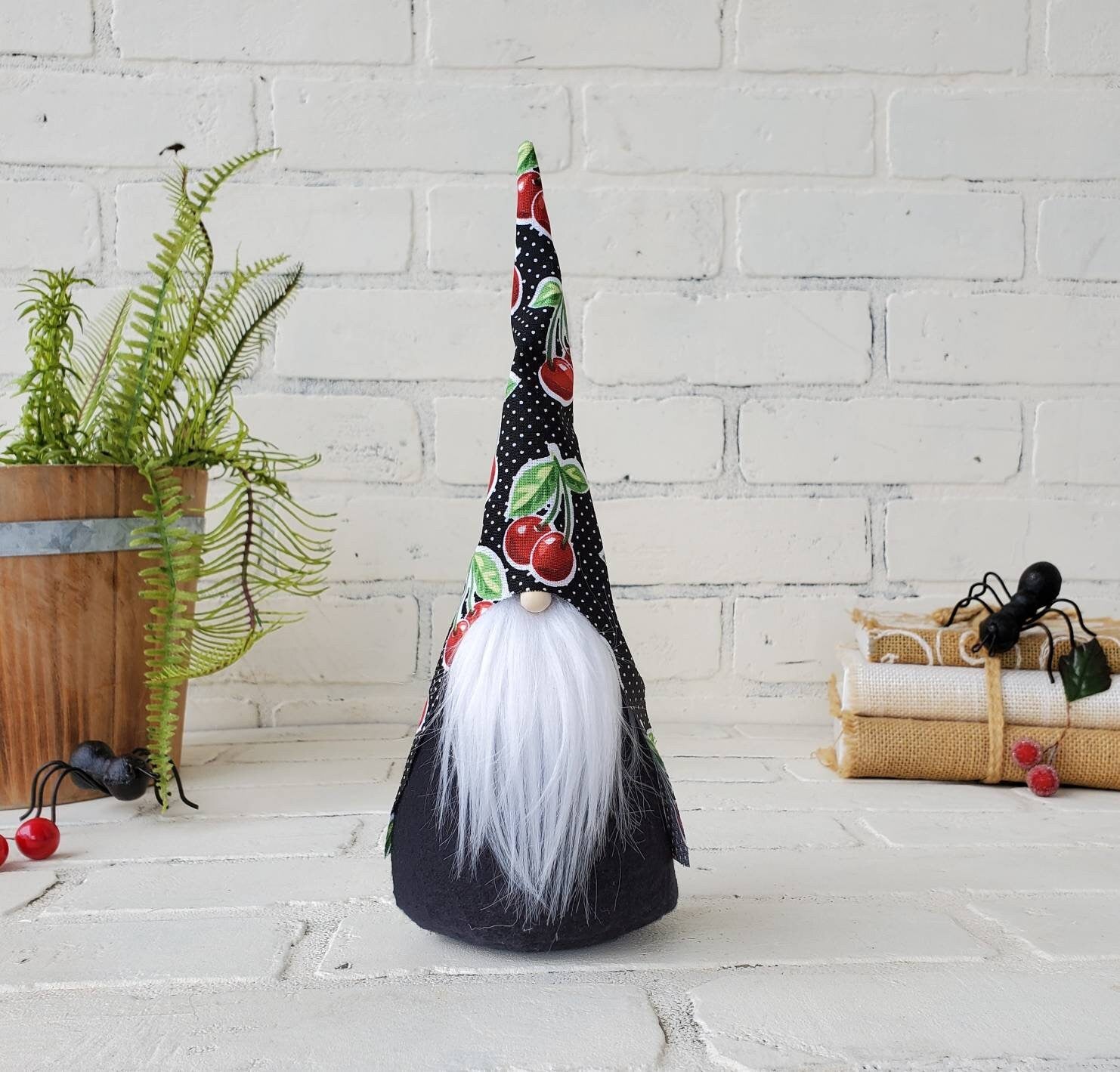 Cherry Gnome with white beard & black body. This handmade KyElle Kreations gnome measures 9 inches. Displayed with faux foliage and seasonal accent decor.