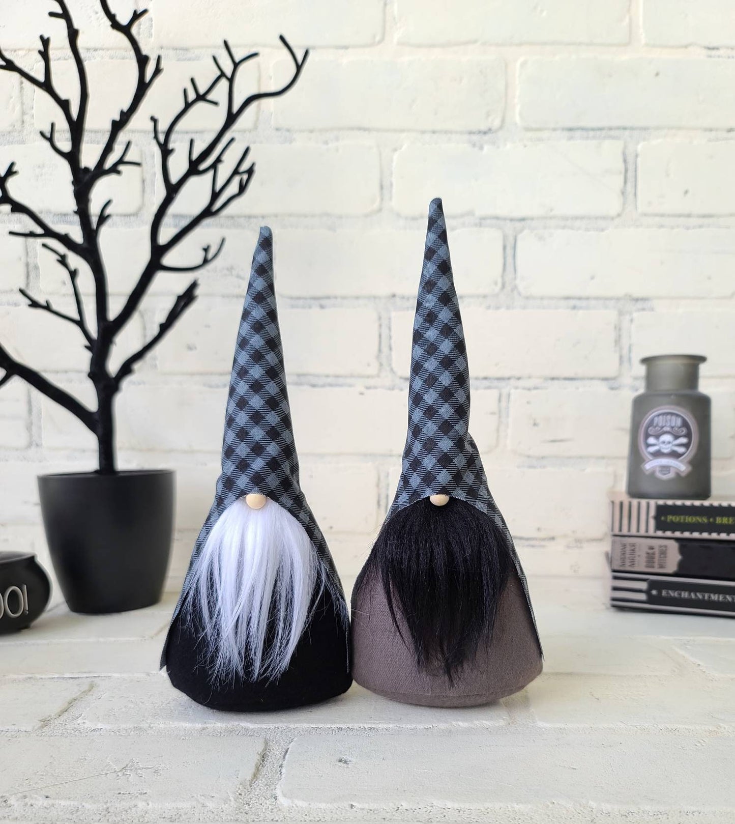 Halloween Gnomes with black & gray buffalo plaid hats, one with white beard & black body. Other with black beard & gray body. These handmade KyElle Kreation gnomes measure 9 inches.. Displayed with faux foliage and seasonal accent decor.