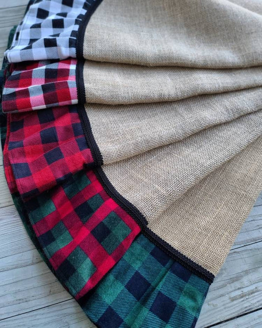 Burlap & Plaid Christmas Tree Skirts fanned to display variety of color options available. Transitioning from white/black, white/black/red, red/black, red/black/green to green/black