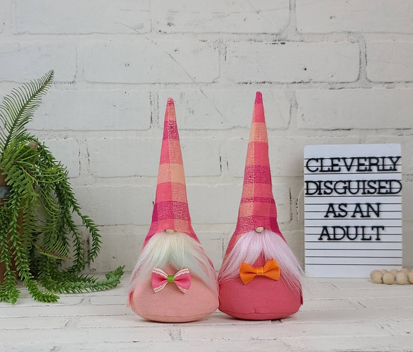 Spring Gnomes with Peach, coral & pale yellow plaid hats.  One with pale yellow beard & peach body. Other has lite pink beard & coral body.These handmade KyElle Kreations gnomes measure 9 inches.. Displayed with faux foliage and seasonal accent decor. 